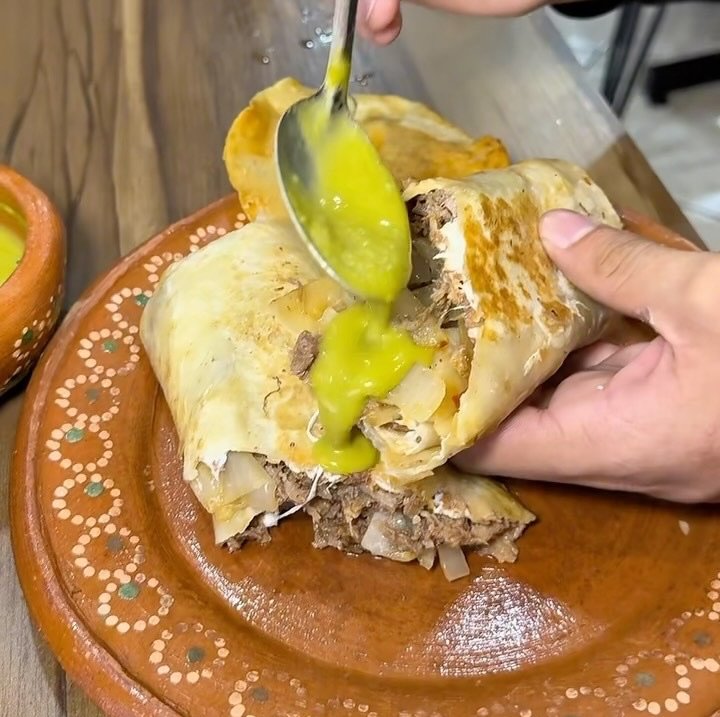 Burrito de barbacoa con salsa verde en plato de barro